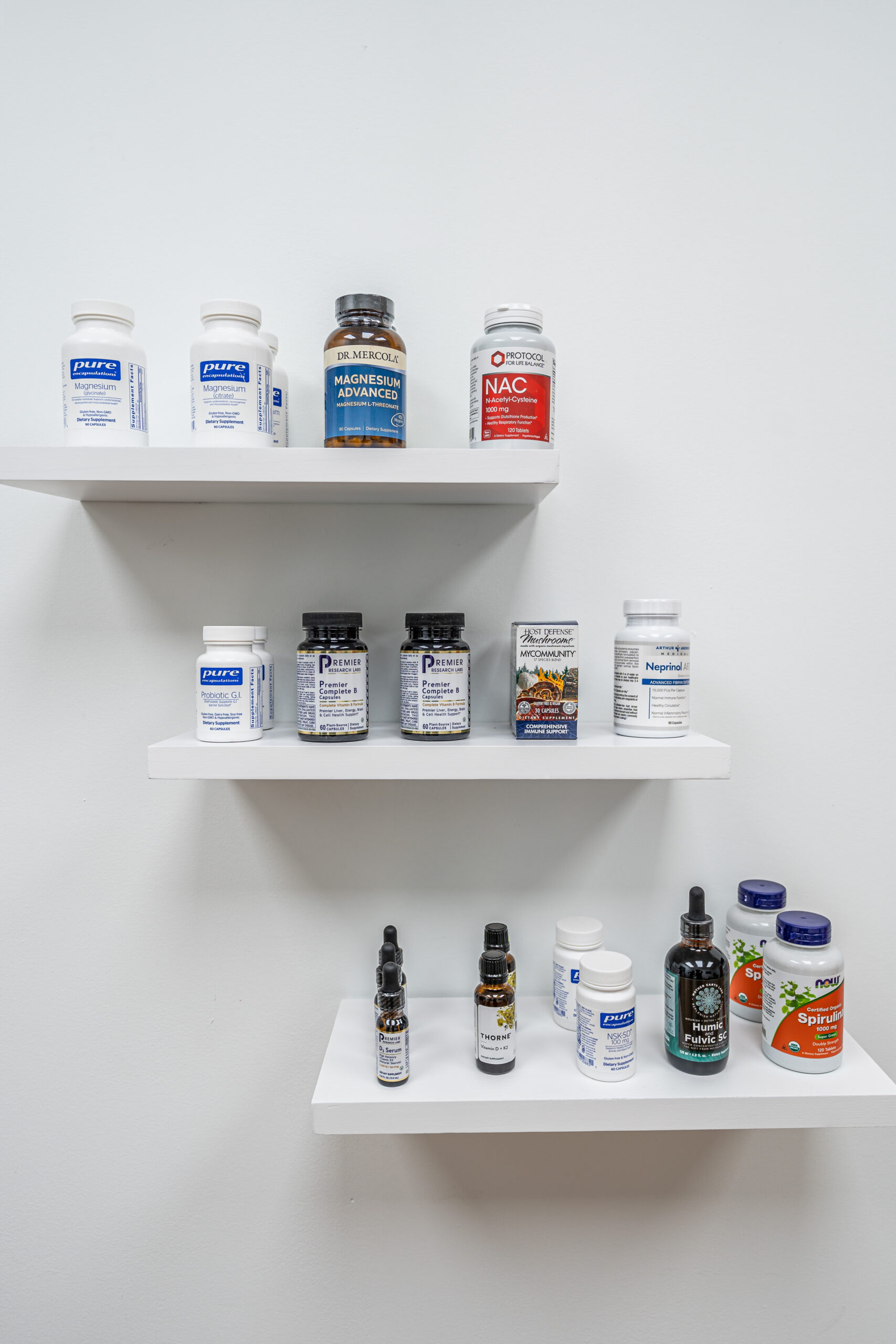 White shelves showcase a diverse array of bottles and containers filled with supplements and oils designed to support and nurture gut health, all set against a simple, clean wall.