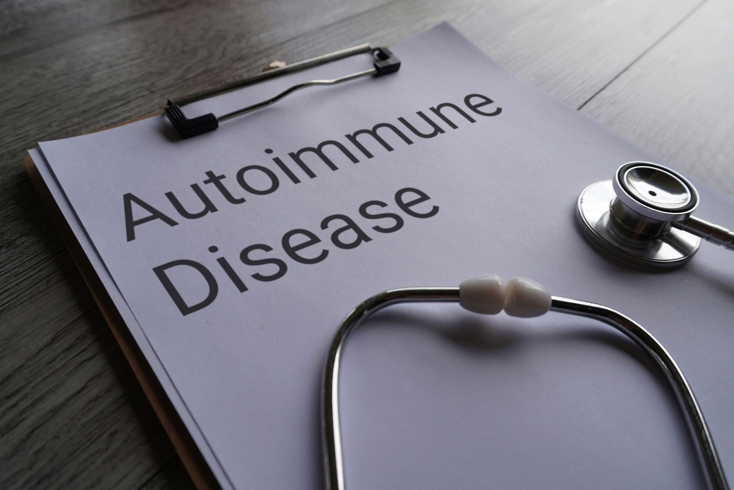 Clipboard with a document titled "Gut Health and Autoimmune Wellness" alongside a stethoscope on a wooden surface.